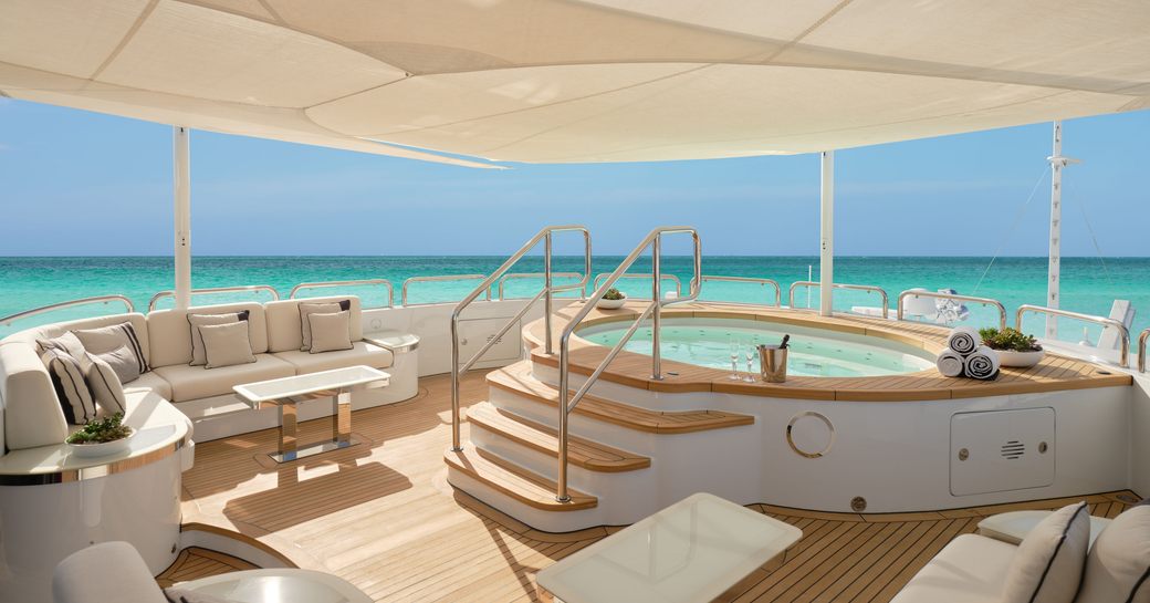 Overview of the sun deck onboard charter yacht GALAXY, on-deck Jacuzzi surrounded by plush white seating. 