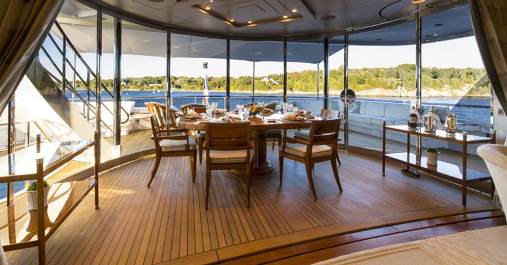 dining area on bridge deck aft with removable full-length glass panels aboard superyacht ‘Blue Moon’ 