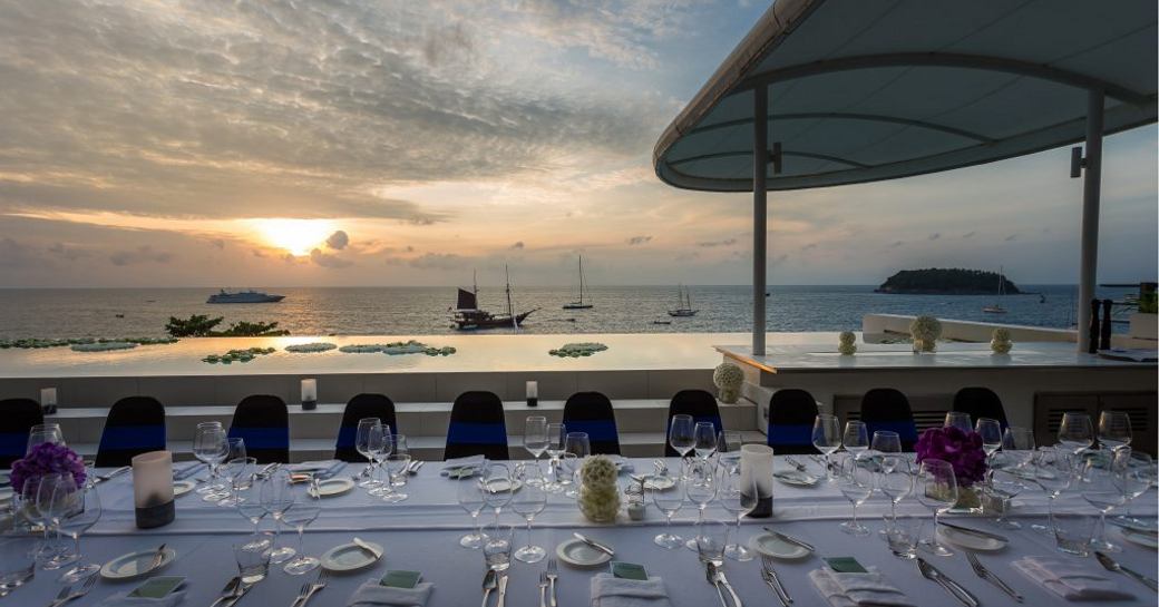 table is set for dinner at the Kata Rocks Superyacht Rendezvous as the sun sets