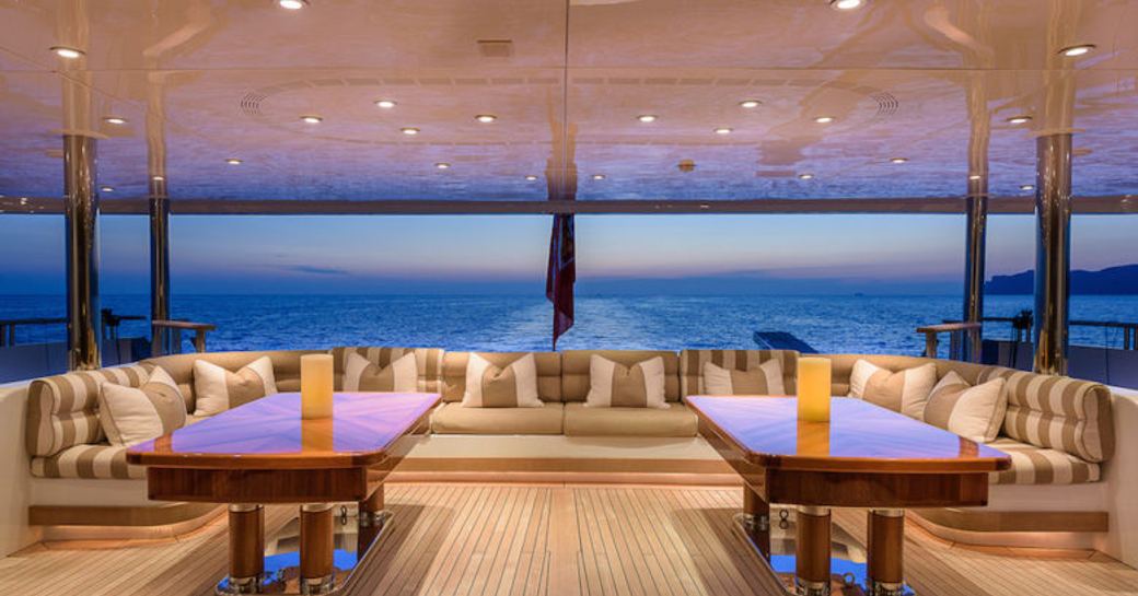 lounging area on aft deck of superyacht BOADICEA as sun sets over the horizon in the Mediterranean