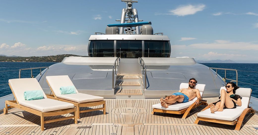 a couple relaxing on sun loungers onboard luxury charter yacht 
