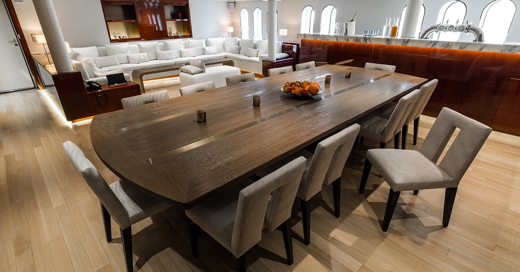 Dining table with sofa in background in main salon of motor yacht Enigma XK