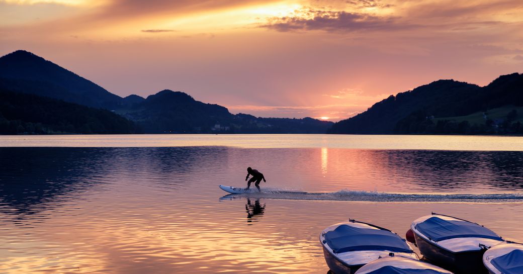 Man using an electric foil surfboard gliding through the water during sunset