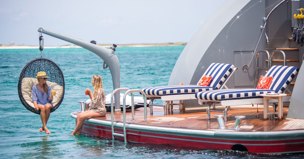 Charter guests relax on the swim platform of motor yacht 'Zoom Zoom Zoom'