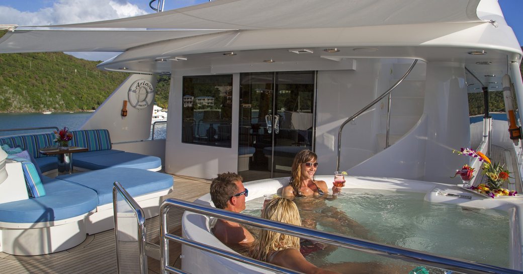 charter guests unwind in the bridge deck Jacuzzi on board superyacht ARIOSO