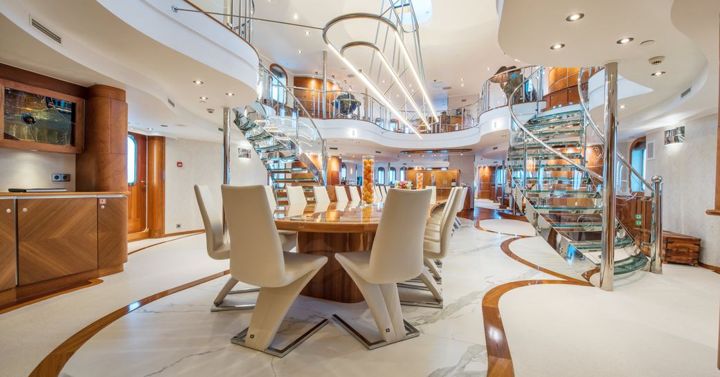 Vast atrium on board superyacht Sherakhan with dining table and chairs