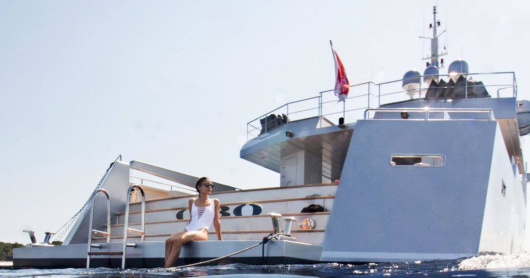 swim platform on superyacht siempre with charter guest sitting on it