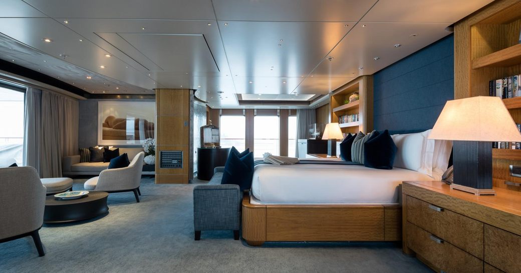 Master cabin onboard superyacht charter OCTOPUS, central berth facing port with seating area and large windows aft
