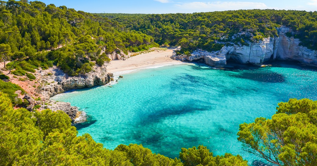 Bright blue water in secluded bay in Mallorca, the Balearic islands, with white sandy beach