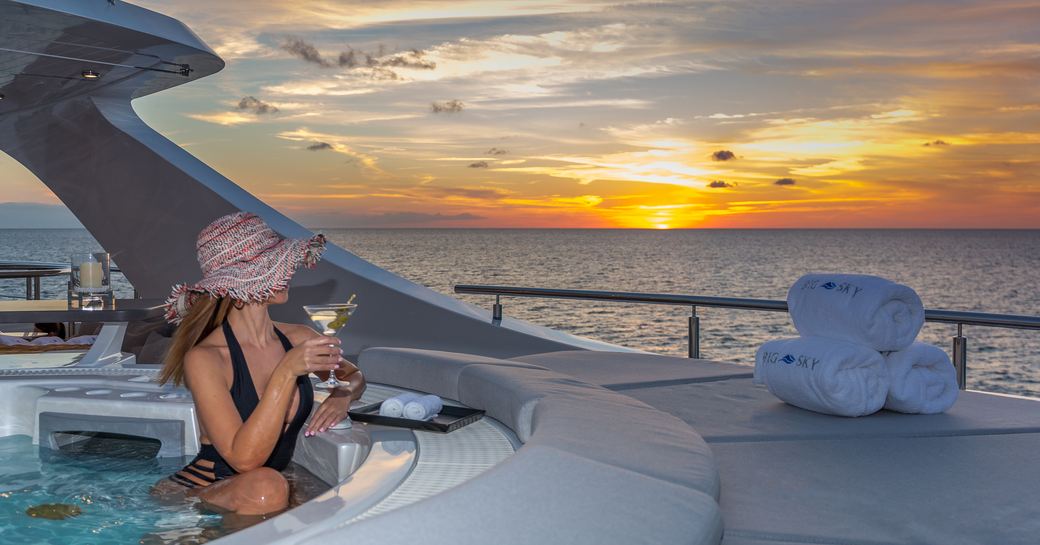 Charter guest watches sunset from the jacuzzi of luxury yacht Big Sky