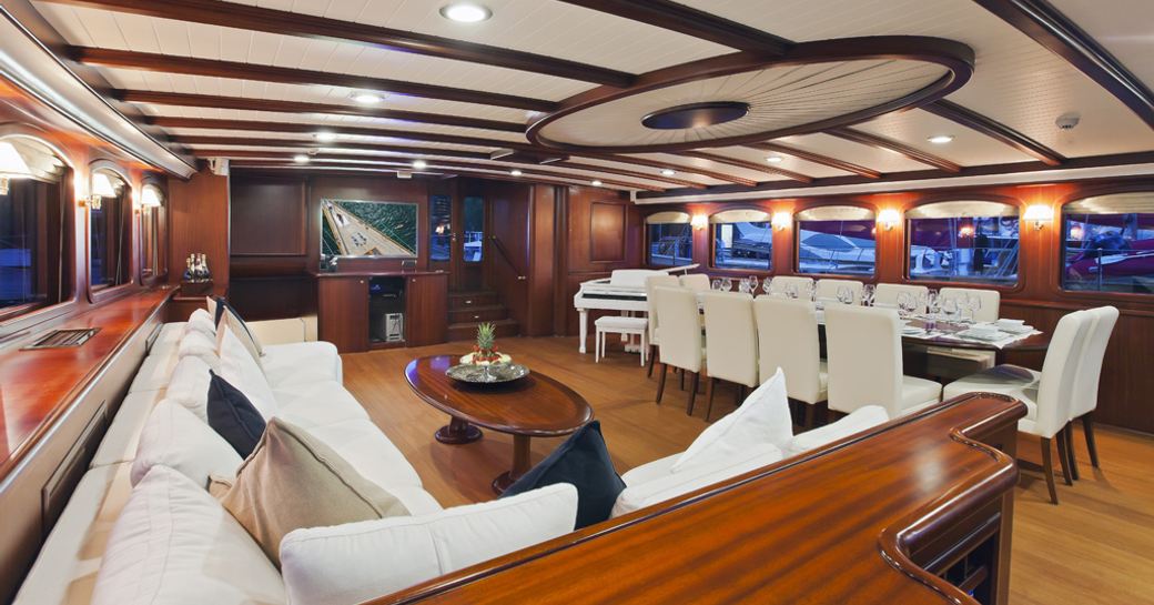 L-shaped sofa, dining table and piano in main salon of charter yacht REGINA 
