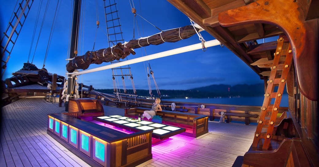 charter guest relaxes in alfresco lounge on deck of luxury yacht Dunia Baru 