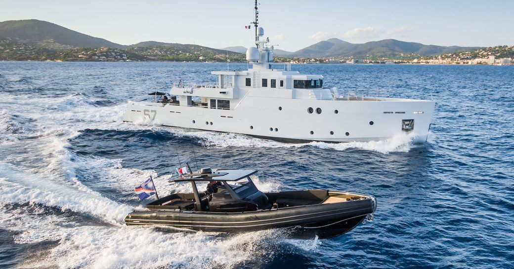 Charter yacht S7 underway, surrounded by sea with a tender running alongside