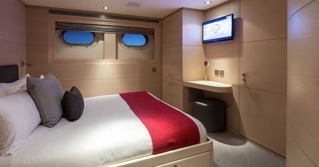Guest cabin onboard luxury yacht charter G3, central berth facing a small TV and dressing table