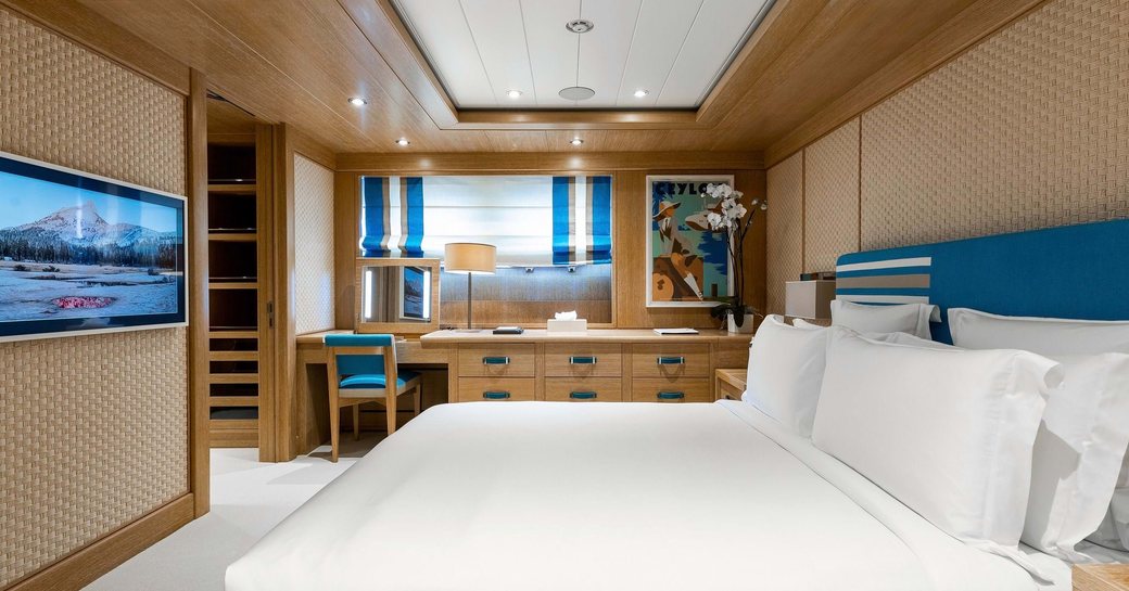 Spacious cabin onboard charter yacht AIFER, with central berth facing port and a wide window with a desk underneath in the background.