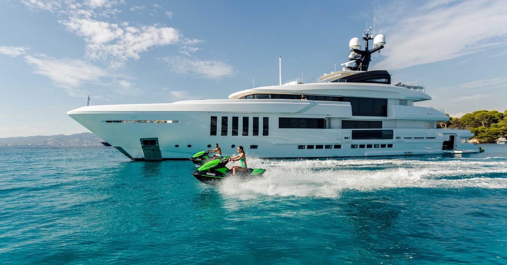 two people jet skiing next to the mega superyacht Ouranos 