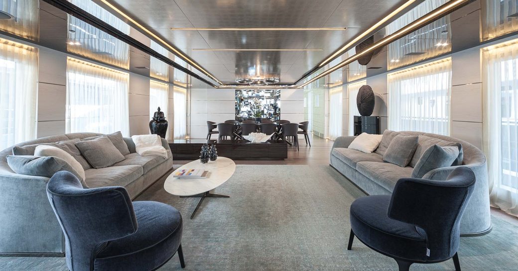 two grey sofas and two navy blue armchairs in the main salon of superyacht ENTOURAGE 