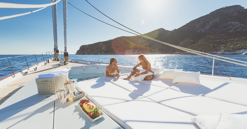 guest takes a dip in the spa pool as another relaxes on sunpads aboard sailing yacht Q
