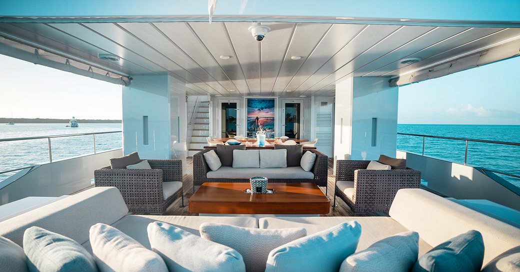 Overview of the aft deck onboard charter yacht ONLY NOW, with exterior lounge area center and surrounding views of the sea