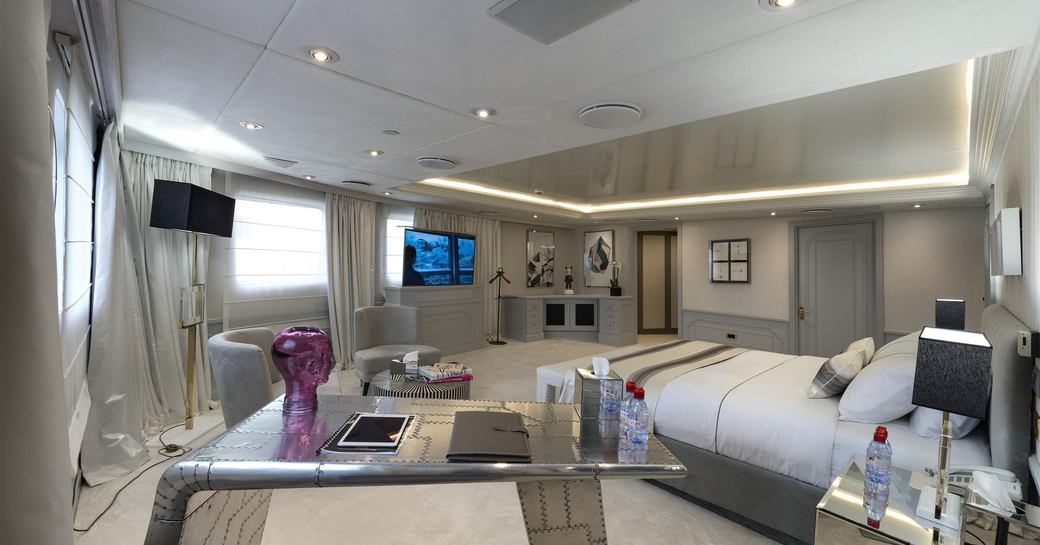 Large cabin on Superyacht CHAKRA with bed facing TV screen and table