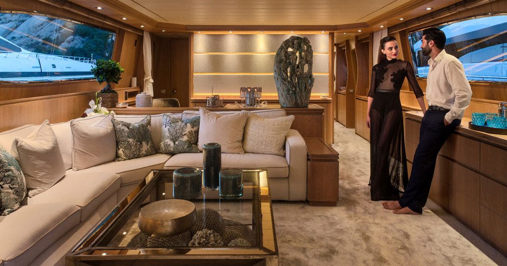 charter guests in evening wear stand in the main salon of motor yacht AMAYA 