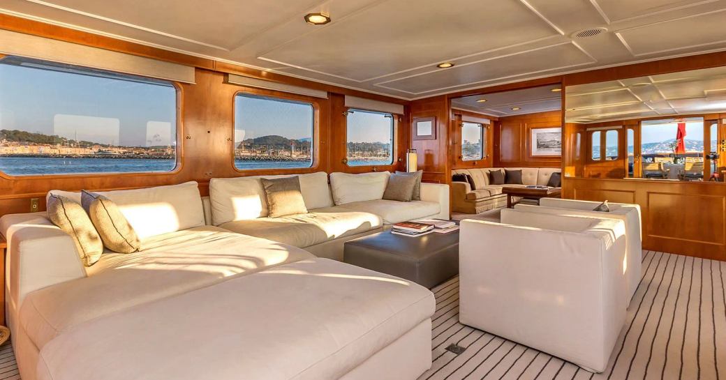 Main salon onboard charter yacht SECRET LIFE, spacious lounge area with plush white seating and many windows