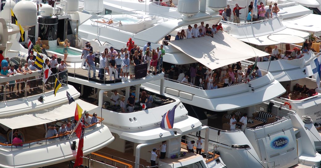 Gathering of yacht charter guests on line up of superyachts watching the Monaco Grand Prix.