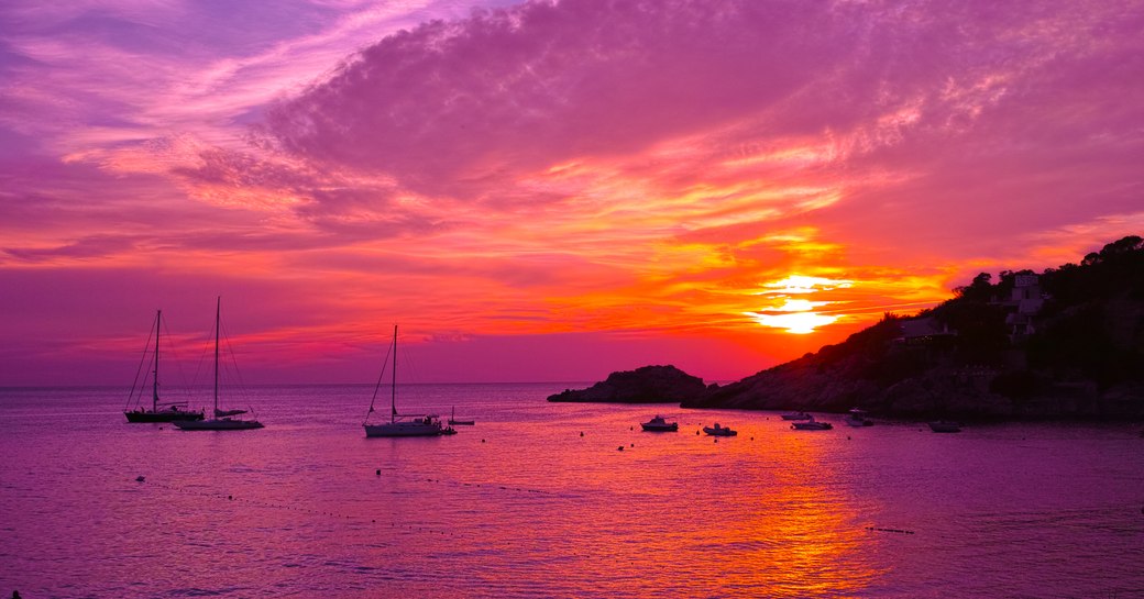 Yachts moored in Ibiza observing pink and purple sky sunset