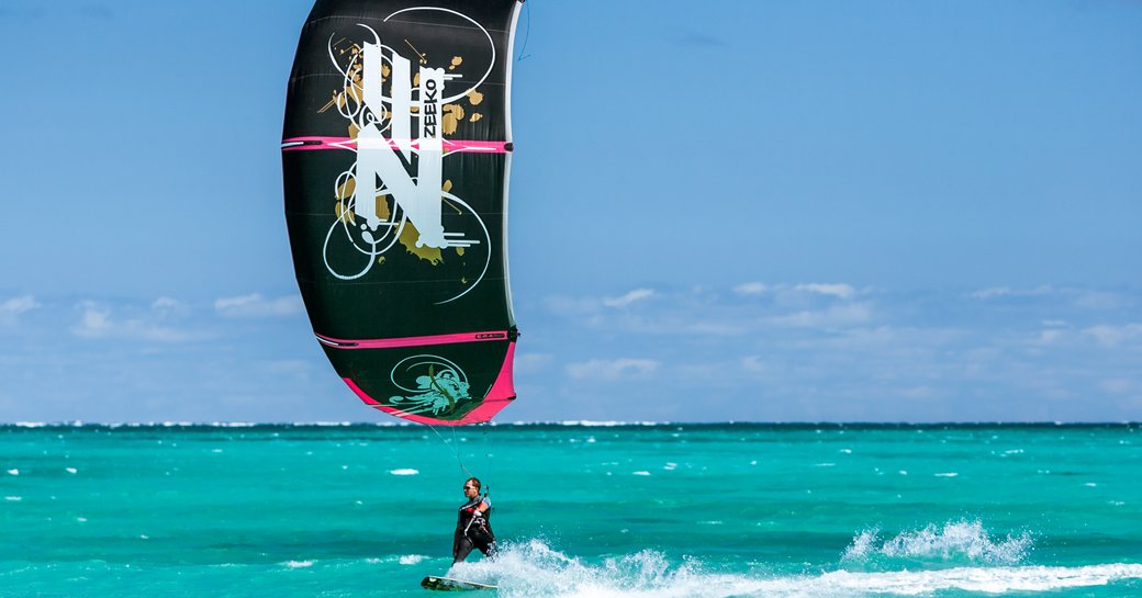 A man performs some windsurfing with a black sail