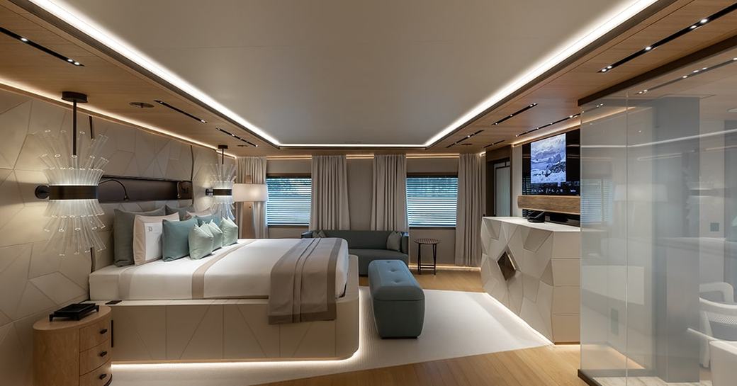 Master cabin onboard charter yacht LA DATCHA, central berth facing aft opposite a wall-mounted TV, with windows in the background