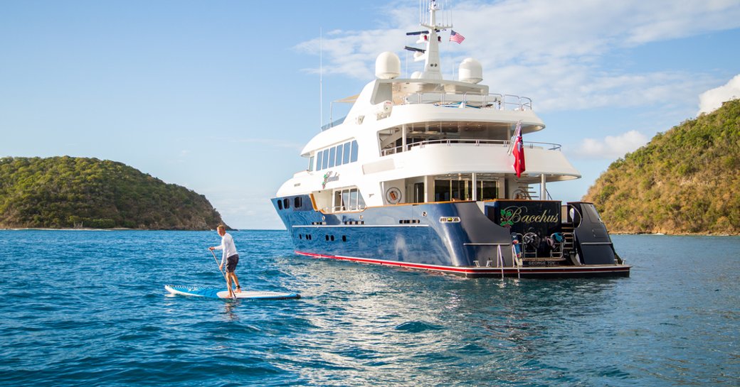 motor yacht BACCHUS anchored on a luxury yacht charter in the Caribbean as charter guests tries out the paddle boards