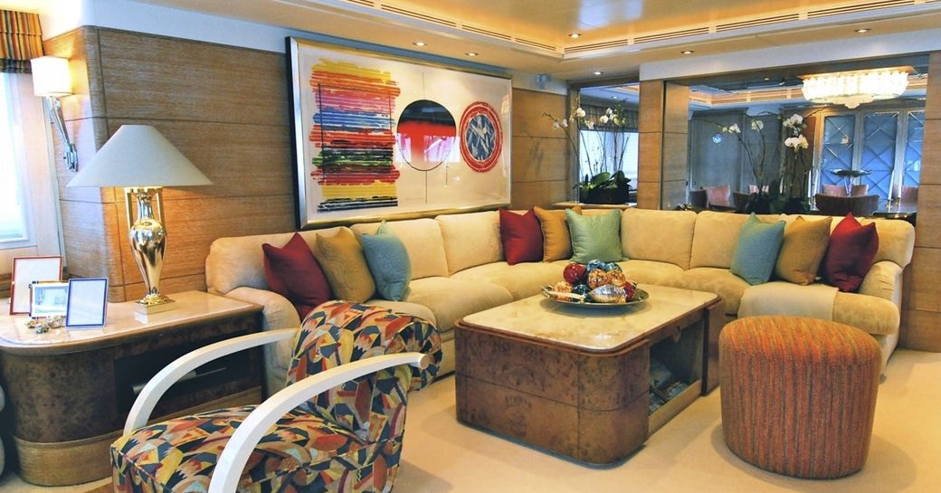 L-shaped sofa with colourful cushions and artwork in main salon aboard superyacht BALAJU 