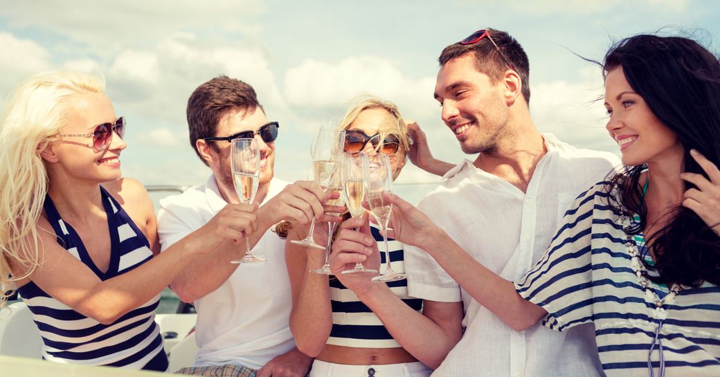 Four people cheers with champagne on a yacht