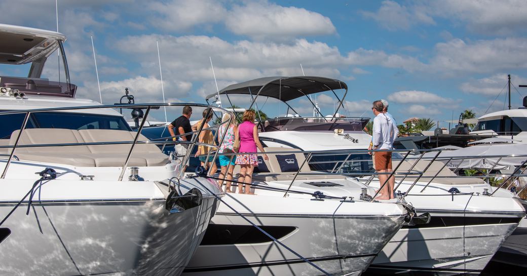 Berthed motor yachts at FLIBS with visitors standing on the bow in discussion