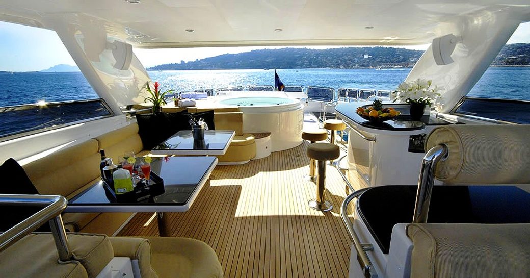 Outdoor living on the sundeck of charter yacht ANNABEL II, with seating areas, bar and jacuzzi in background