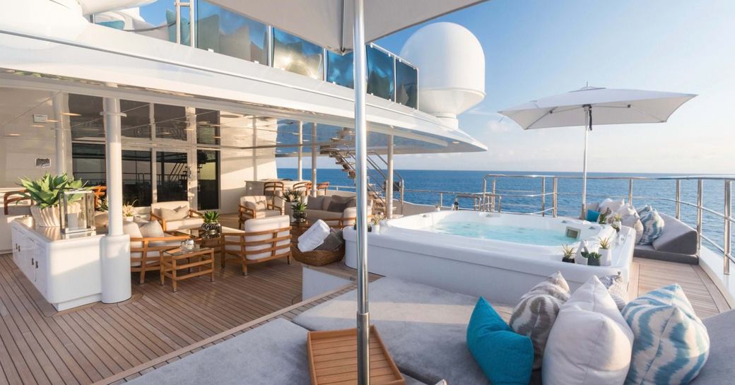 Aft deck onboard charter yacht JOIA THE CROWN JEWEL, deck Jacuzzi adjacent to sunpads and parasols