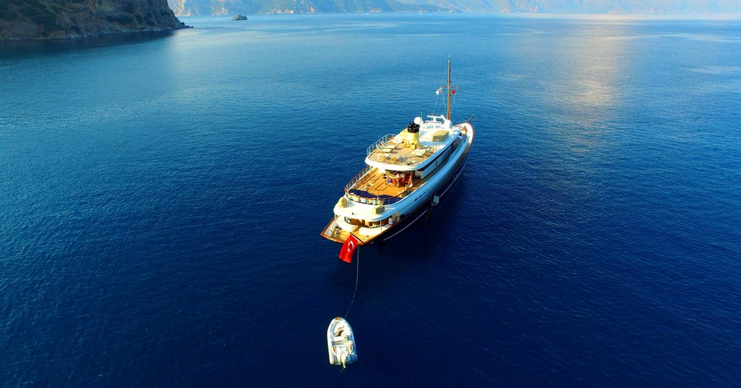 Charter yacht CLARITY alongside her tender in open blue water, aerial shot