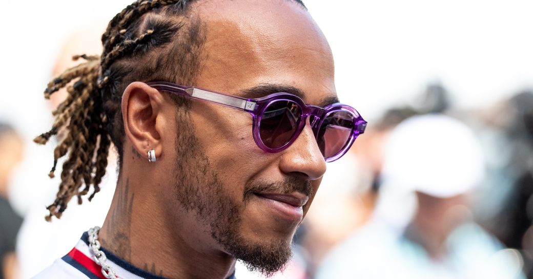 Side shot of Lewis Hamilton wearing white shirt and sunglasses.