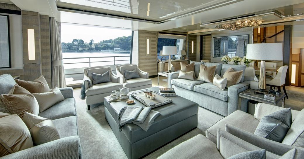Lounge area in the main salon onboard charter yacht LADY VICTORIA, with abundant plush seating and full length windows aft