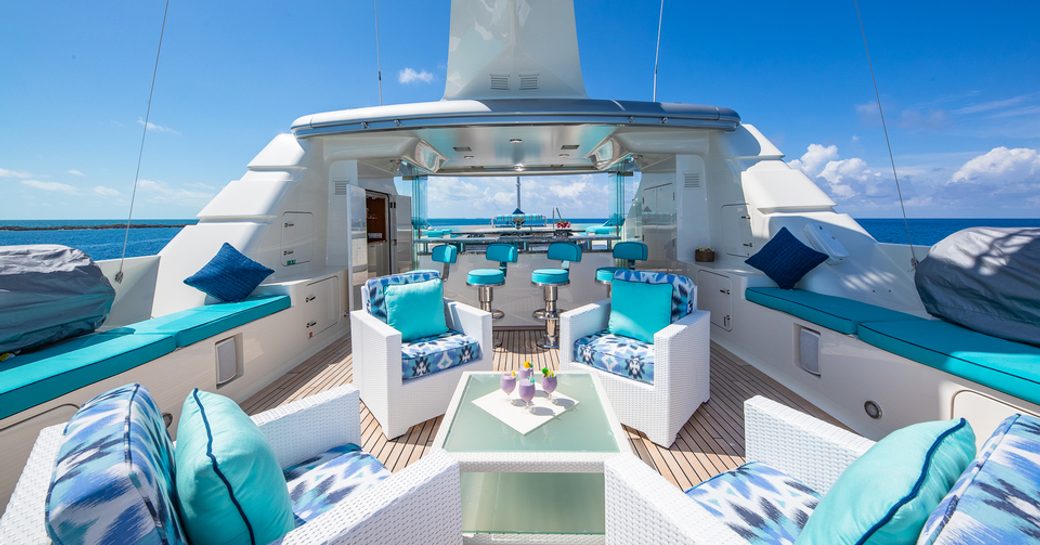 Overview of the sun deck onboard charter yacht NITA K II with plush blue seating and a wet bar aft