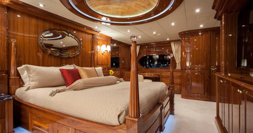 owners cabin on board luxury yacht, with polished wood and large bed in centre
