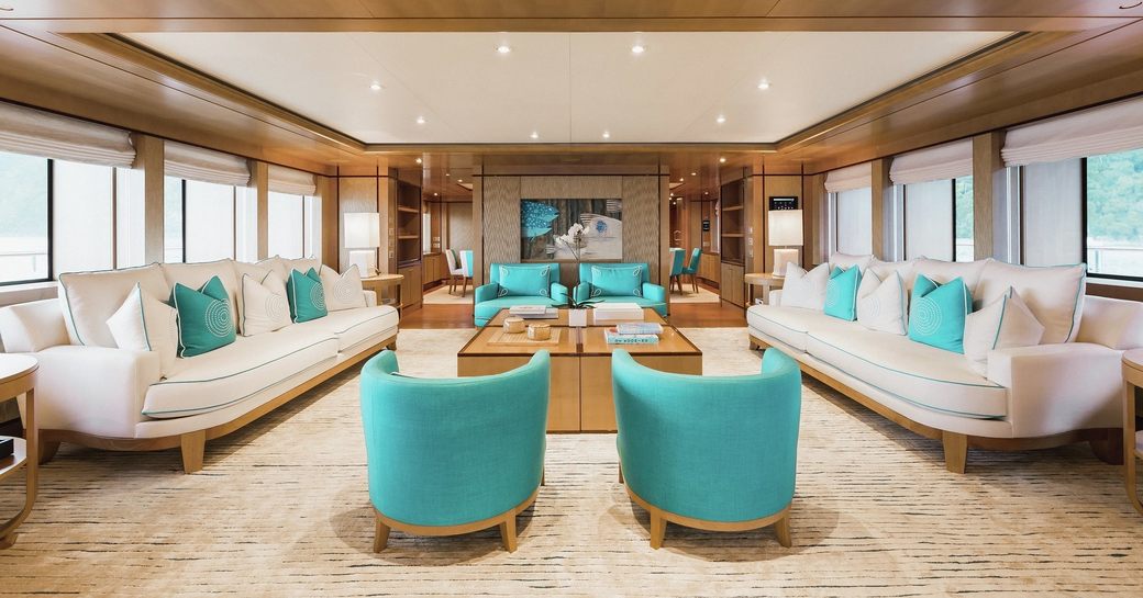 cream sofas and teal armchairs create a sociable lounge area in the main salon of charter yacht Ramble on Rose 