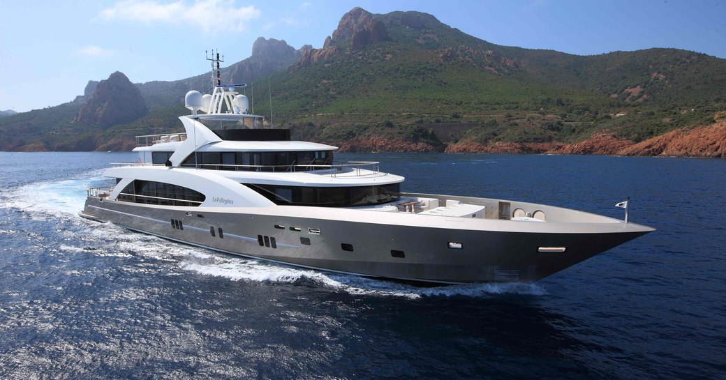 Charter yacht LA PELLEGRINA underway, surrounded by sea with elevated terrain in the background