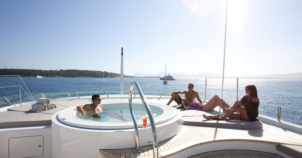 guests relax in Jacuzzi and on surrounding sun pads on board superyacht SPIRIT 