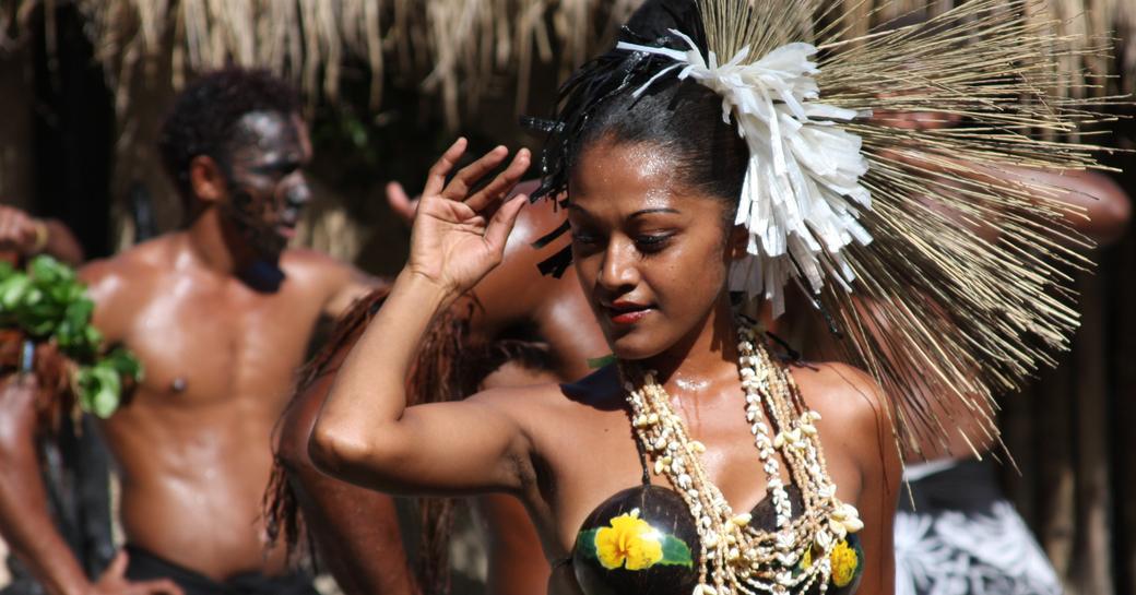 A woman in traditional Fijian dress dancing with other tribe members