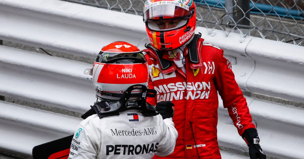 Two Formula 1 drivers geared up and conversing on track.