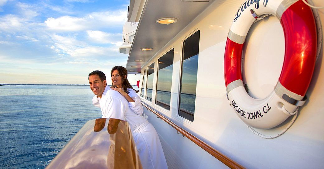 A man and woman look out to sea from the exterior of luxury yacht LADY J