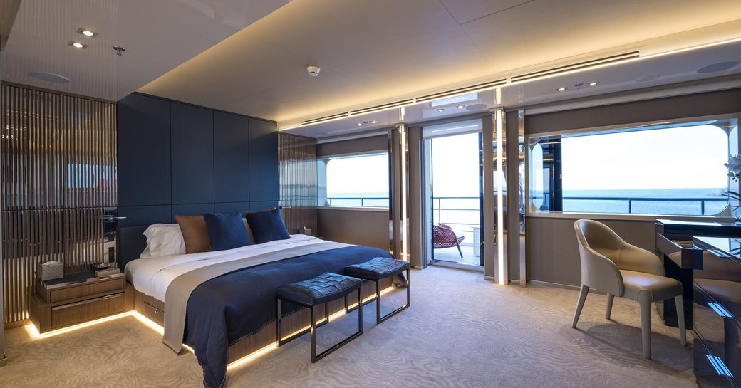 Spacious cabin onboard M/Y SERENITY, berth on portside facing office desk and chair, with private balcony in background