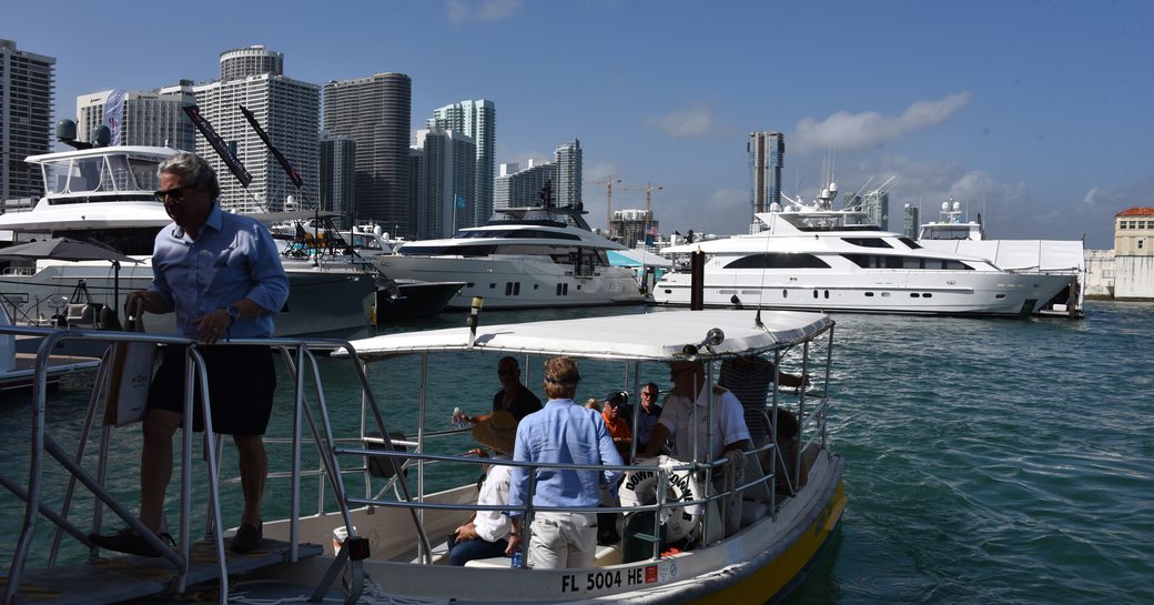 A man walking down a walkway off of his tender from his voyage between superyachts at the 2020 miami yacht show