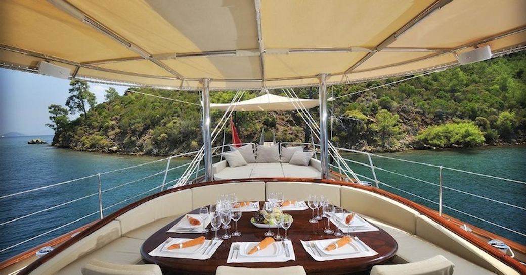 aft deck dining under sun awnings and sofa beyond on board superyacht REGINA